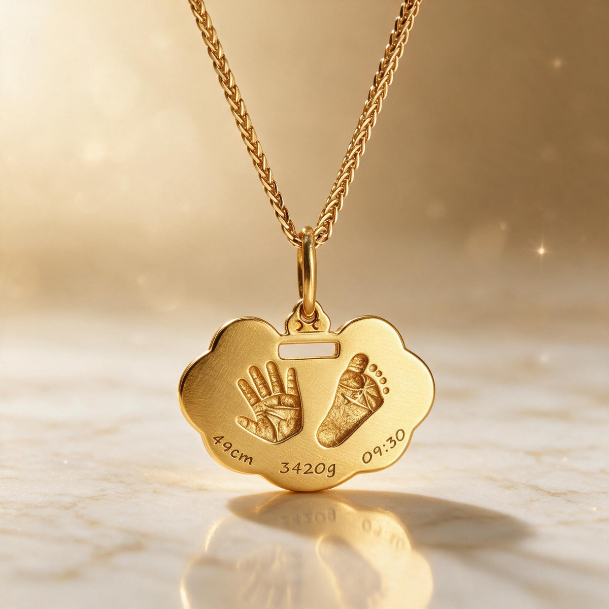 Gold-tone handprint and footprint pendant standing on a softly lit surface.