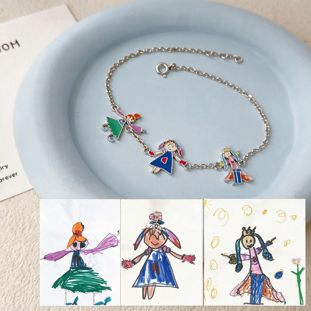 Silver-tone charm bracelet on a blue dish, with the original drawings of three figures shown below.