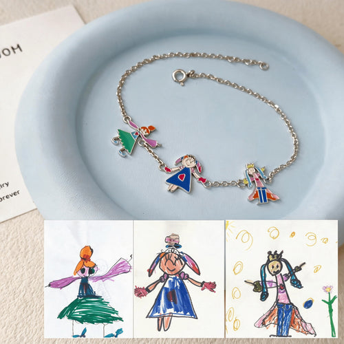 Silver-tone charm bracelet on a blue dish, with the original drawings of three figures shown below.
