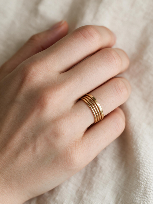 Three slim gold-tone stacking rings worn together on one finger.