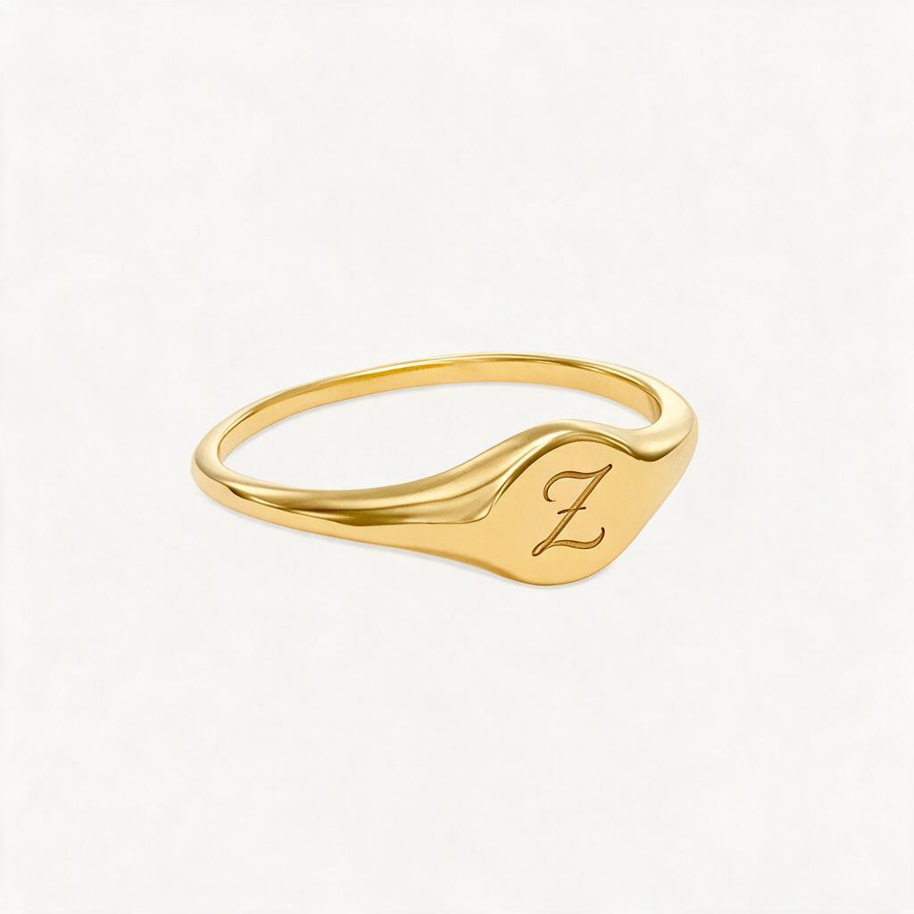 Gold-tone initial signet ring with a script Z on its curved face, shown at an angle.