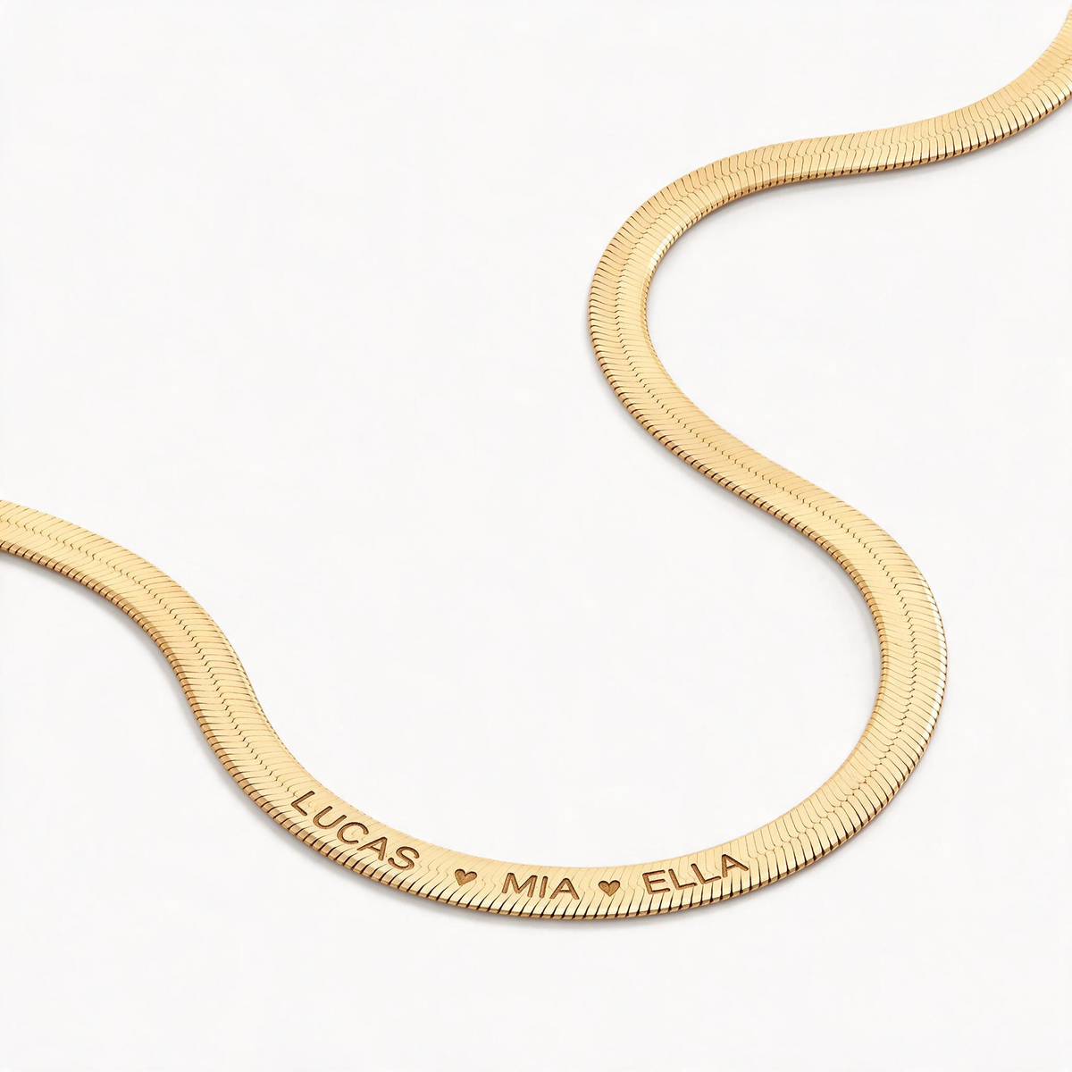 Close-up of a herringbone necklace engraved with Lucas, Mia and Ella separated by hearts.
