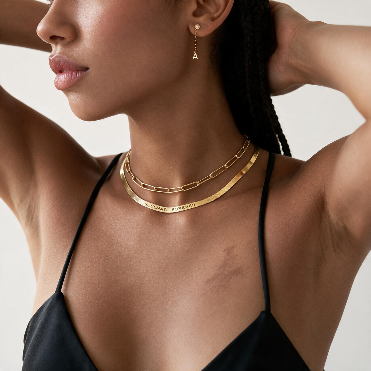 Woman wearing a gold-tone herringbone necklace layered with a paperclip chain.