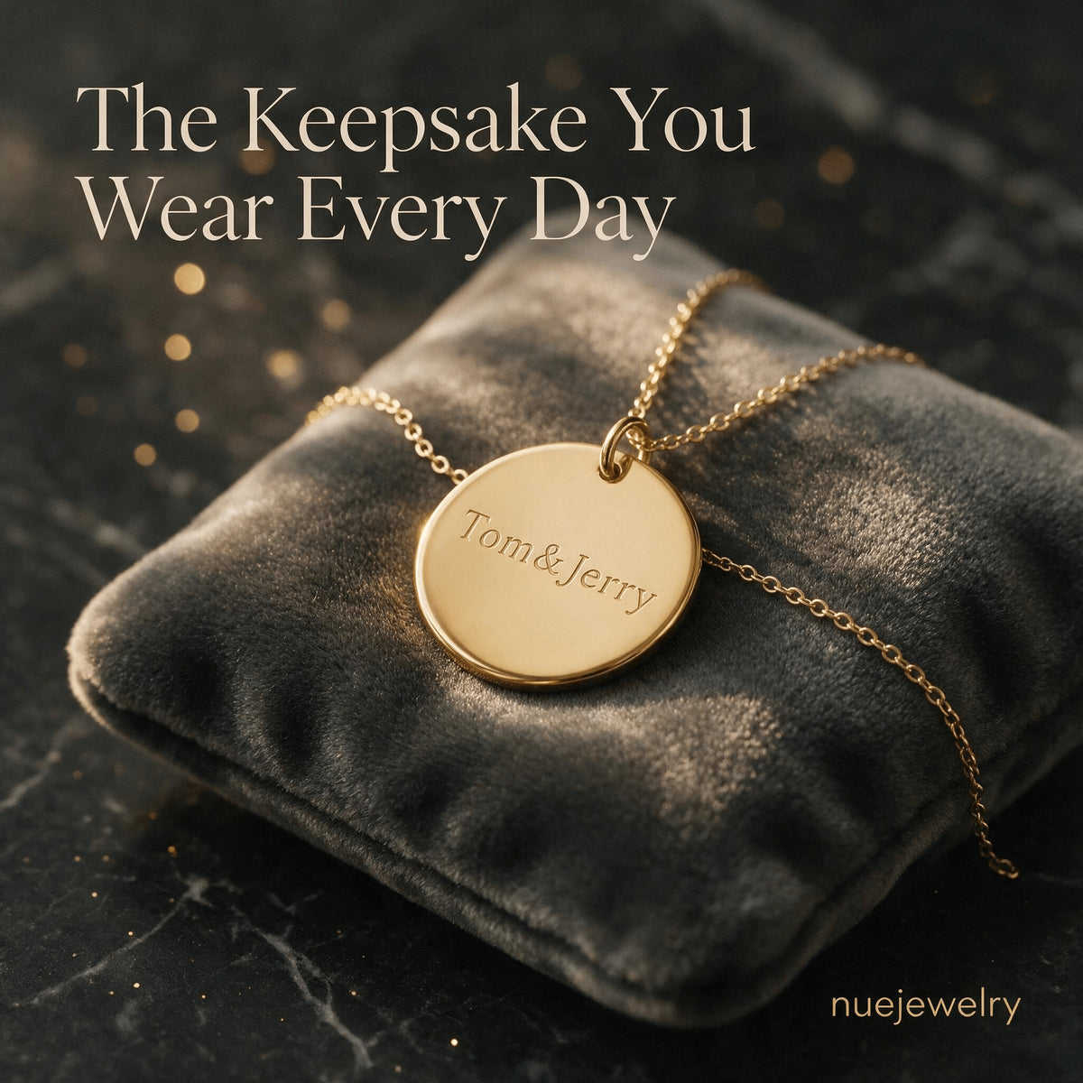 Round gold-tone pendant engraved with Tom and Jerry resting on dark fabric.